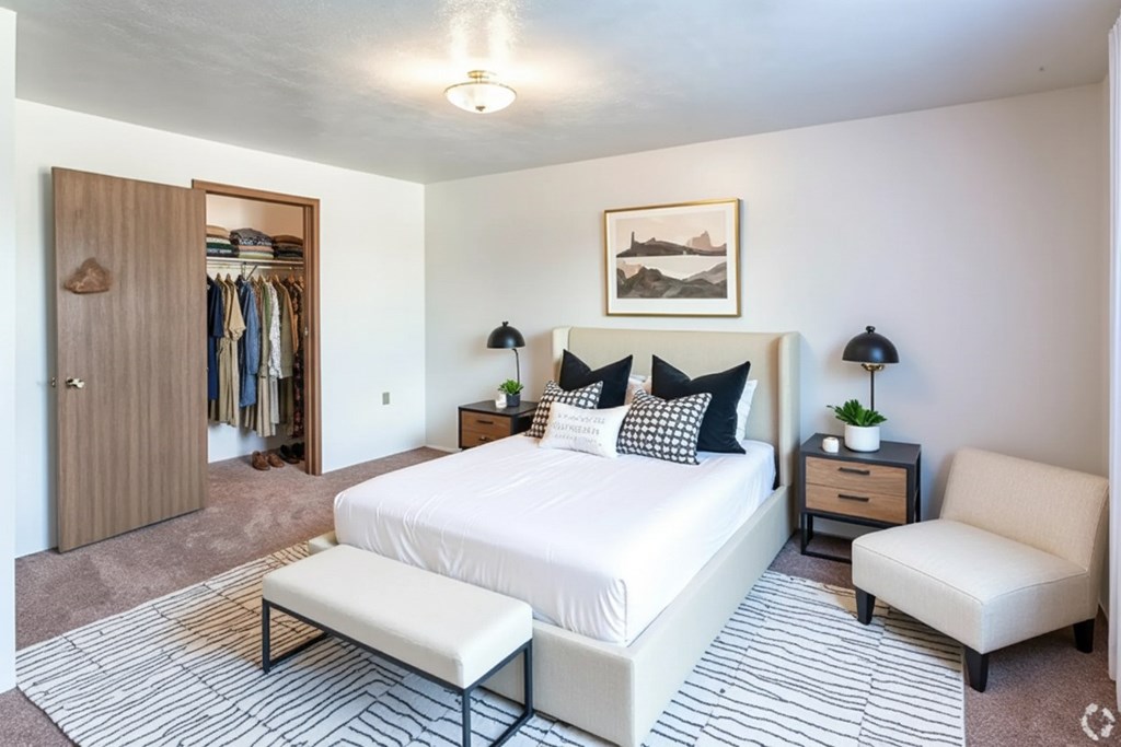 A bedroom with a large bed, a chair, and a wardrobe.