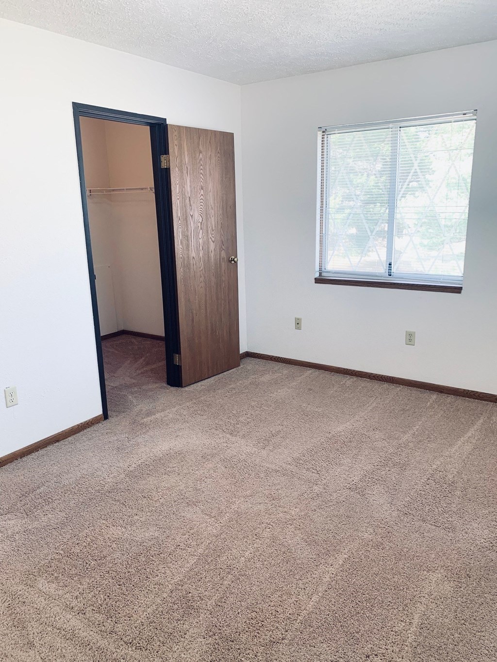 an empty bedroom with a closet and a window
