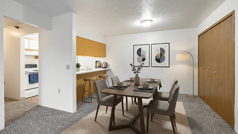 A dining room with a table set for two and a kitchen area in the background.