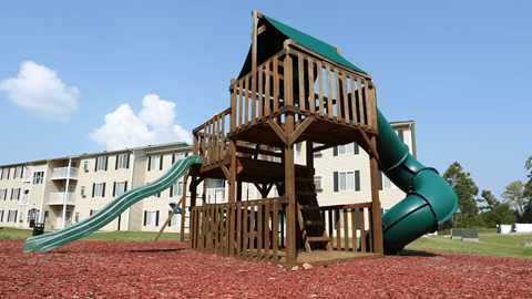 A wooden playground structure with a green slide.