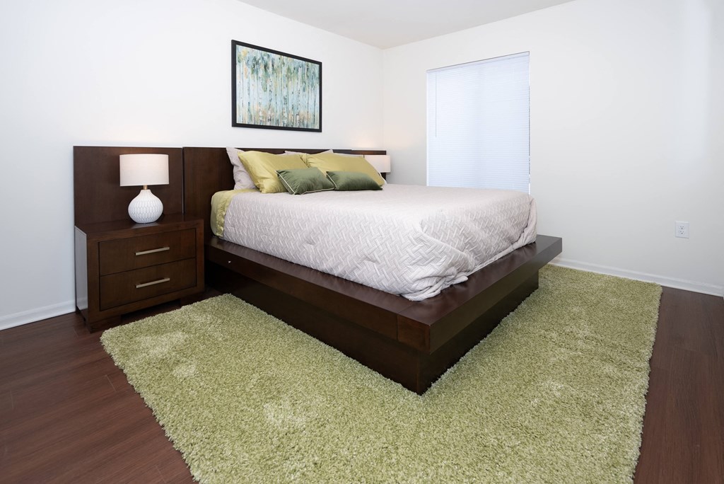 A bedroom with a bed, nightstand, and rug.