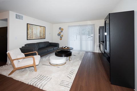 A black couch sits in a living room with a wooden chair and coffee table.