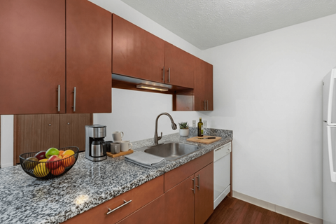 A kitchen with brown cabinets and a marble countertop.