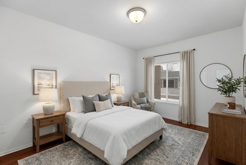 A bedroom with a large bed and a window with curtains.