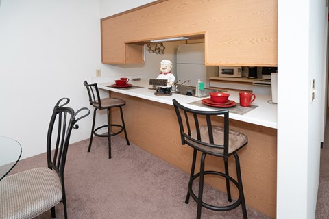 a kitchen with two bar stools in front of a counter with two chairs