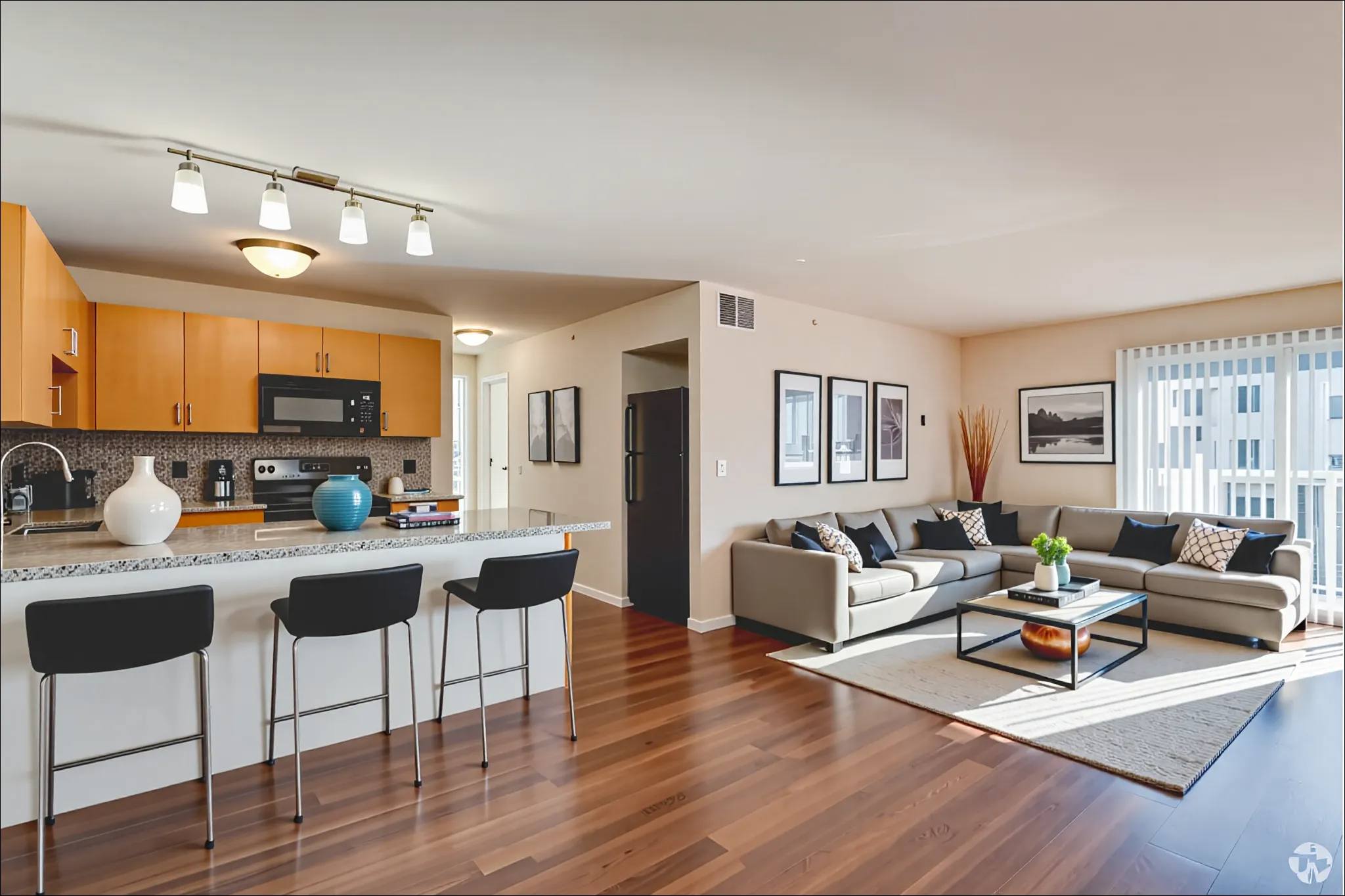 A modern kitchen with a bar area and a living room with a couch.
