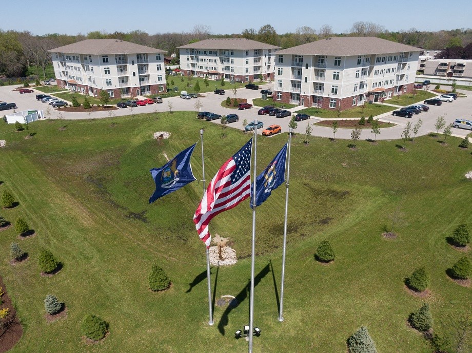 a group of flags flying in a field in front of buildings
