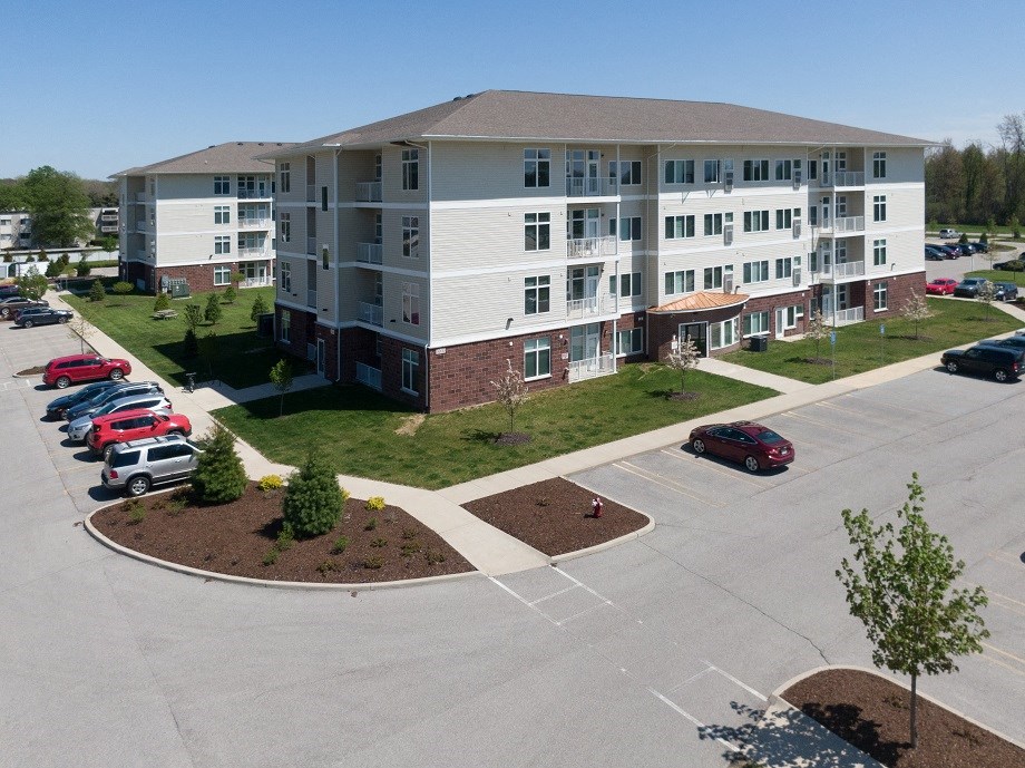 an aerial view of an apartment building in a parking lot with cars