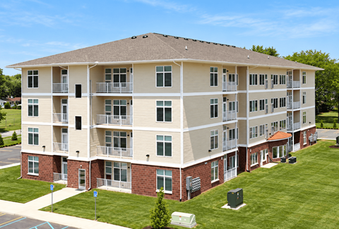 A large apartment building with a grassy lawn in front.