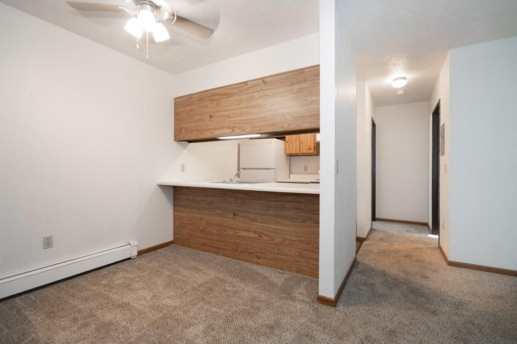 a living room with a kitchen and a ceiling fan