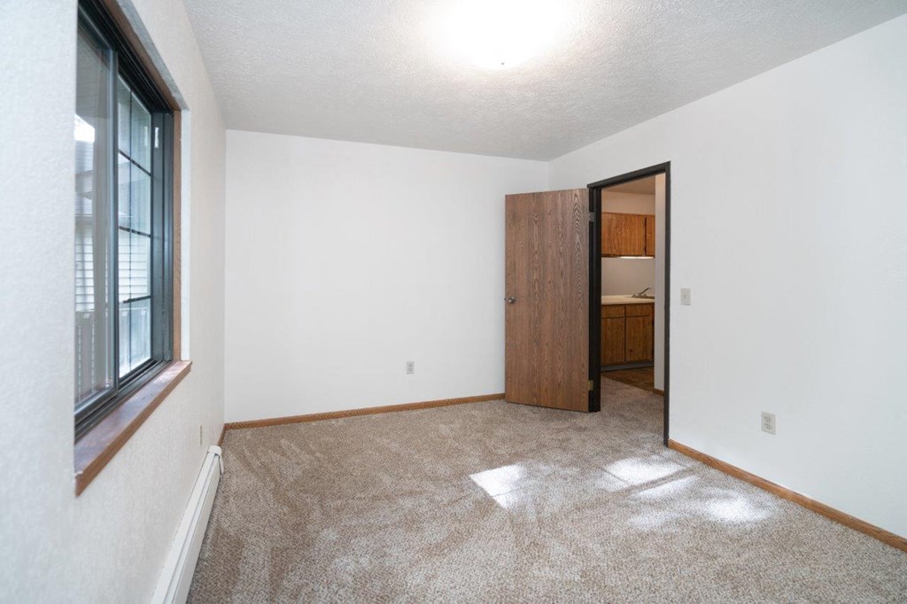 an empty living room with a window and a door to a bathroom