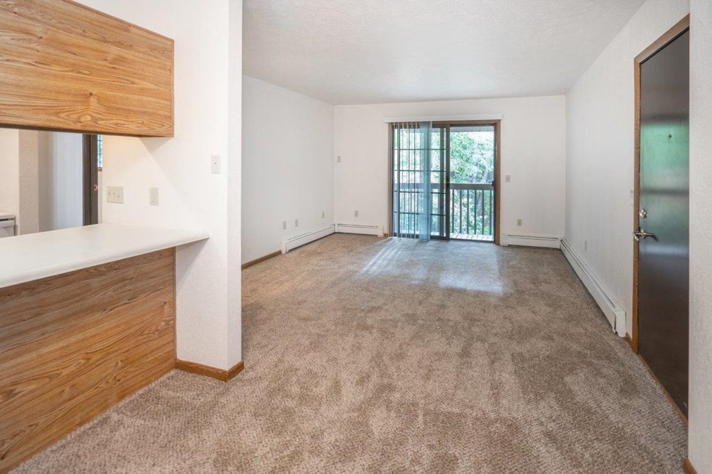 an empty living room with a door to a balcony