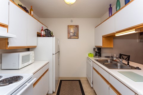 A kitchen with white cabinets and a white microwave.