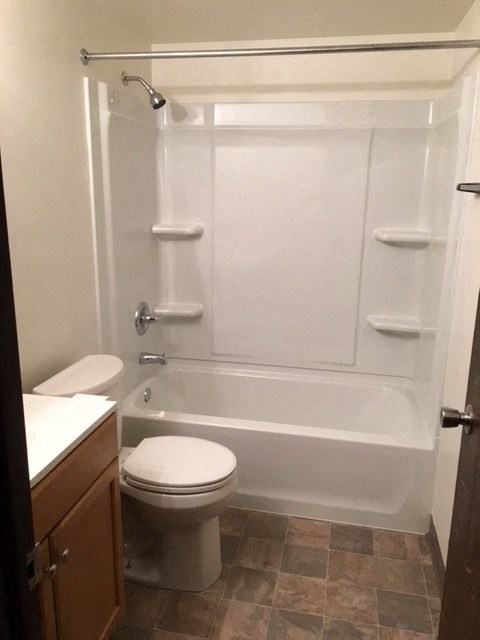 a white bathroom with a toilet and a tub