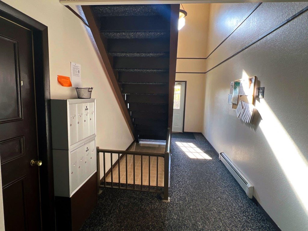the hallway of a home with stairs and a dresser and a refrigerator