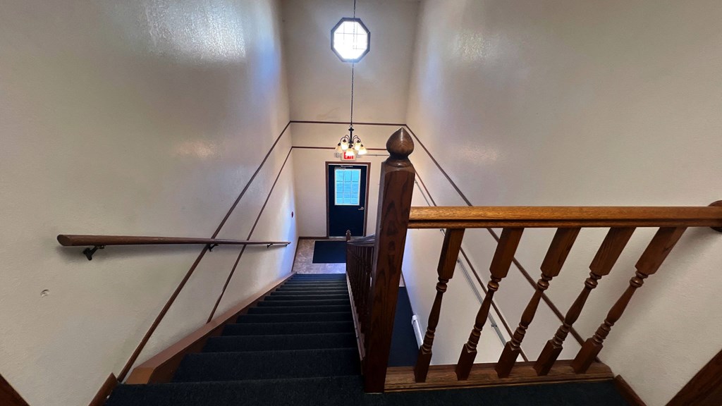a stairway with a wooden railing and a blue door with a light above it