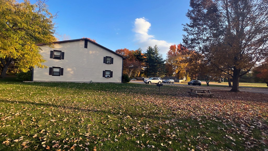 a house with a picnic table in a field with leaves on the ground