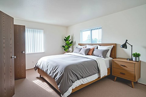 A bedroom with a bed, nightstand, and a plant.