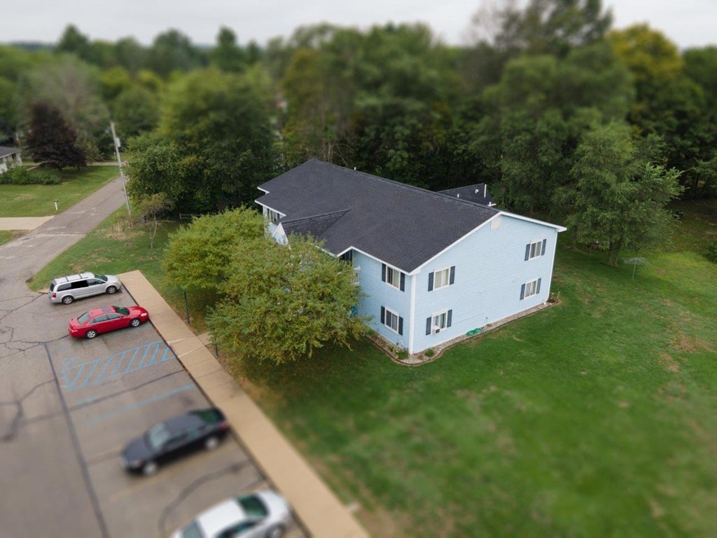 a white house with a gray roof and a parking lot