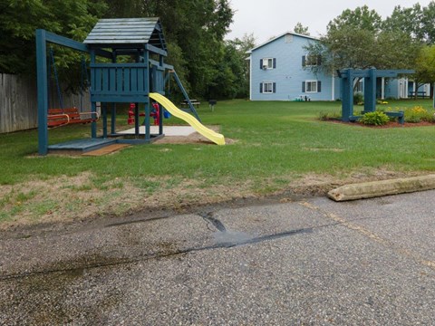 a playground with a yellow slide in a park