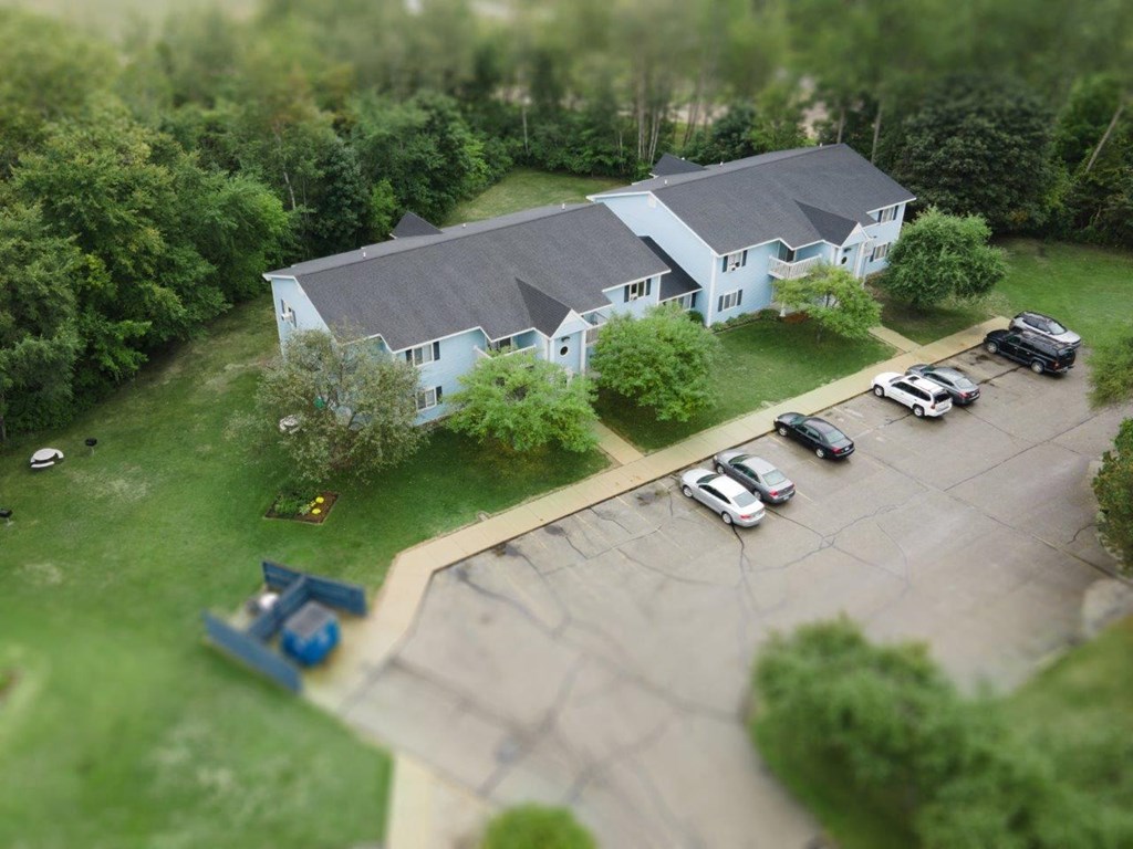 an aerial view of a white house with cars in a parking lot