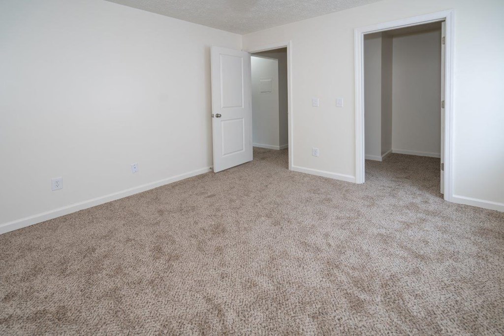 a bedroom with carpet and a door to a closet