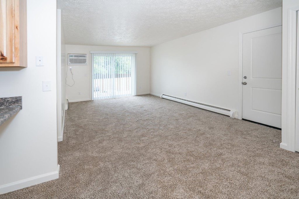 an empty living room with a door to a balcony