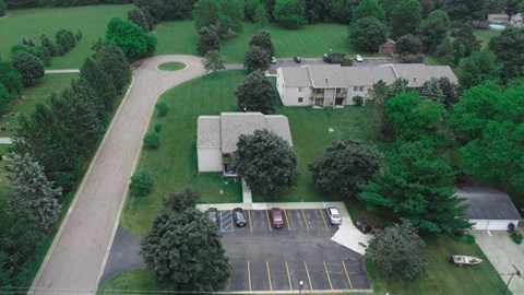 an aerial view of a house with a parking lot and a yard with trees