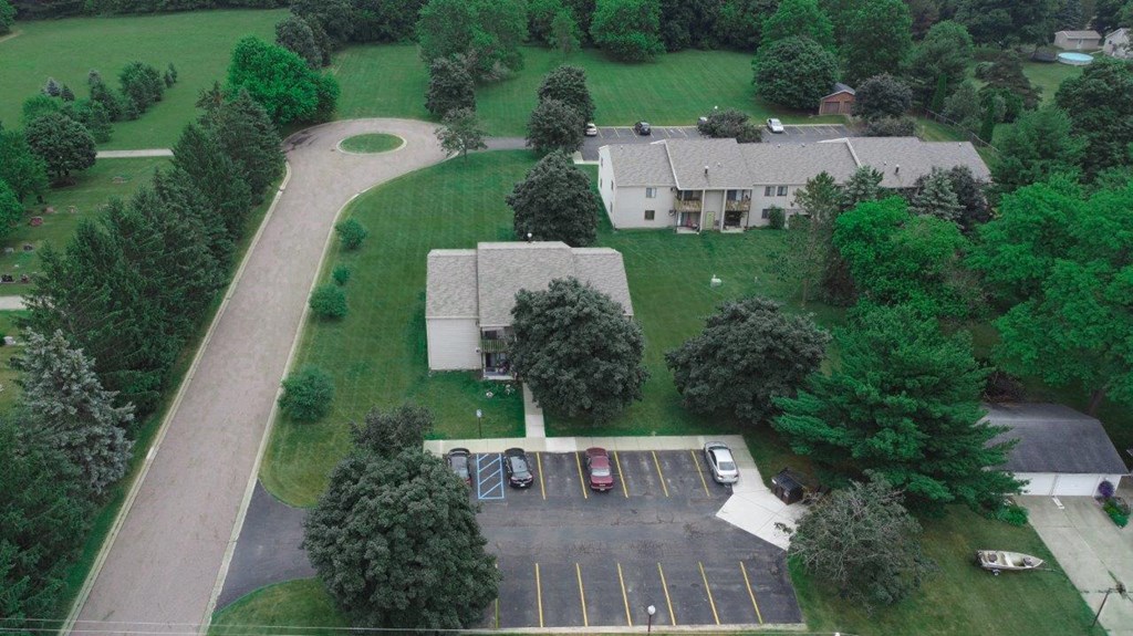 an aerial view of a house with a parking lot and a yard with trees