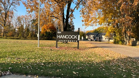 a sign on the side of a road in front of a park