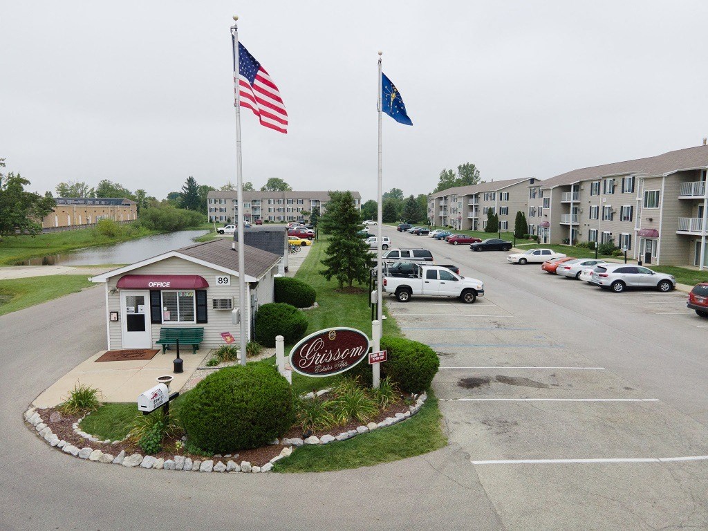 an empty parking lot with two flags in front of an apartment building