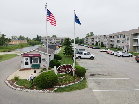 an empty parking lot with two flags in front of an apartment building