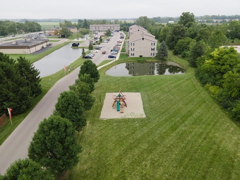 an aerial view of a park with a pond and buildings