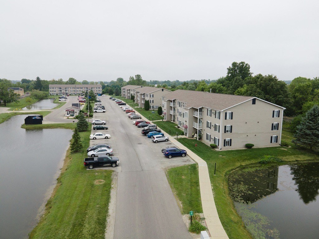 an aerial view of a street with cars parked next to a river