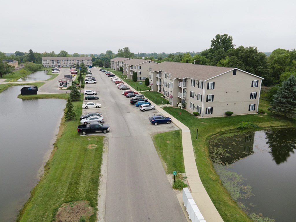 an aerial view of an apartment complex with a river and cars parked on the street
