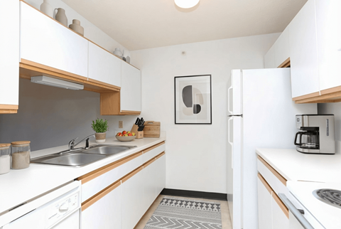 A kitchen with white cabinets and a grey floor mat.