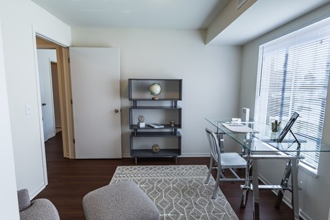 A living room with a grey couch, a glass table, and a television on a stand.