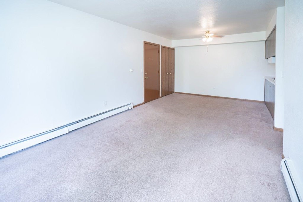 an empty living room with a white wall and carpet