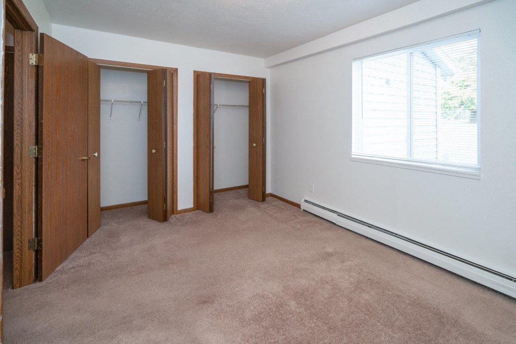 a bedroom with two closets and a window and a carpet