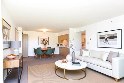 A living room with a white couch, a coffee table, and a dining table with chairs.