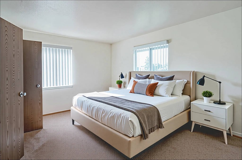 A bedroom with a bed, nightstand, and window.