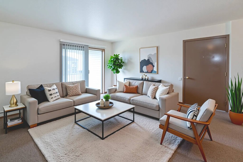 A living room with a grey couch, a coffee table, and a wooden chair.