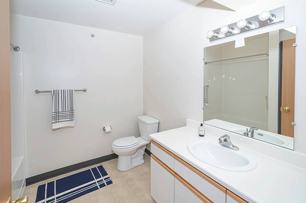 A bathroom with a toilet, sink, and mirror.