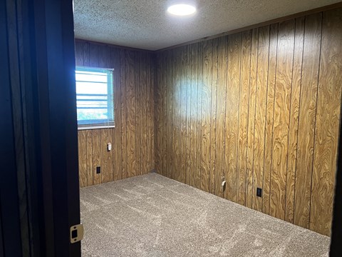 an empty room with wood paneled walls and a window