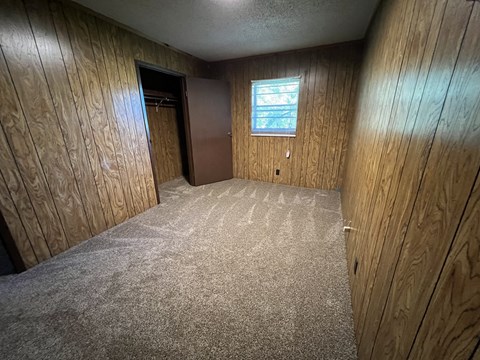 an empty room with wooden walls and a door and a window