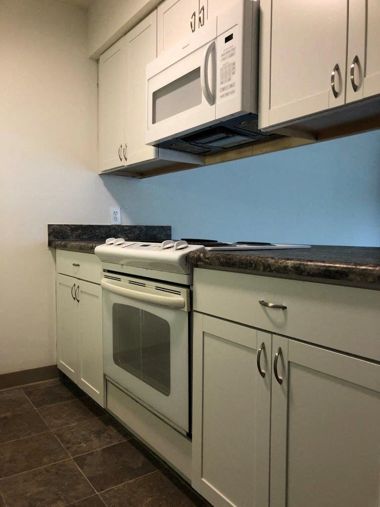 a kitchen with white cabinets and a white stove top oven