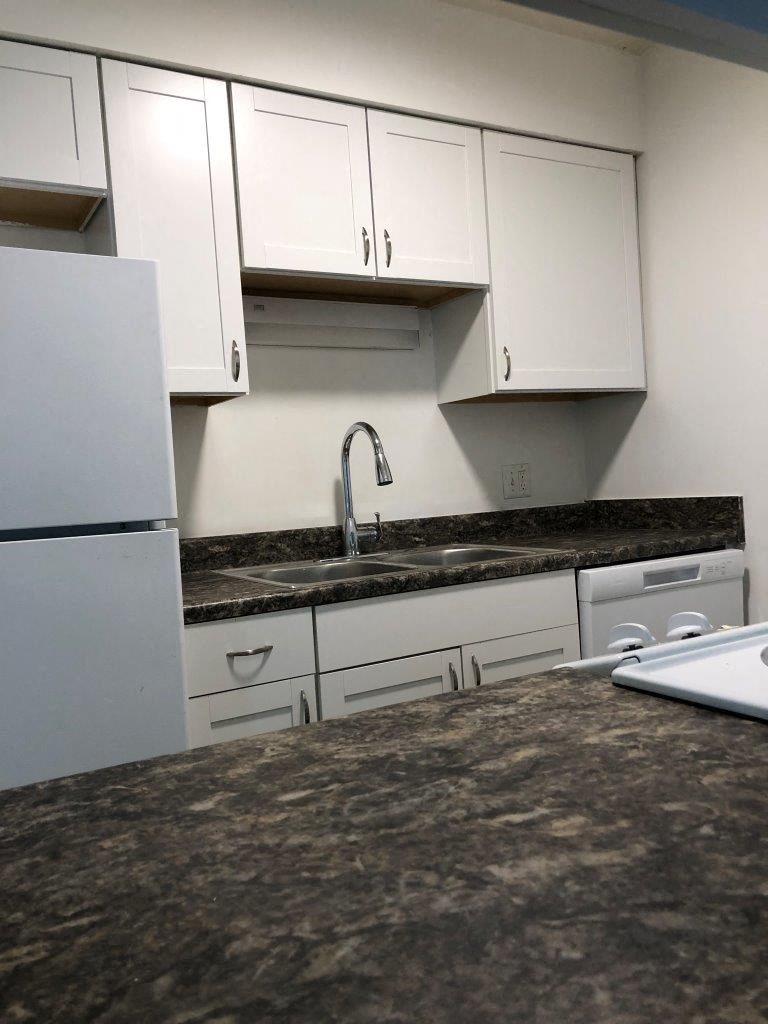 a kitchen with white cabinets and a granite counter top
