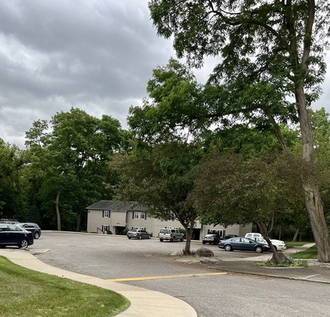a parking lot with trees and cars in front of a house