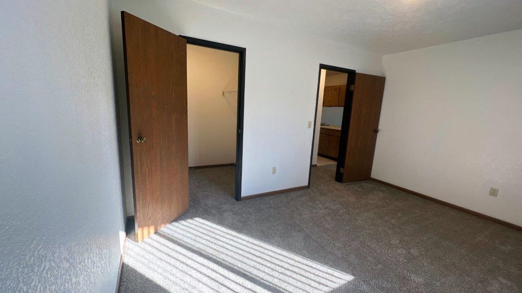 a living room with a door to a bathroom and a closet