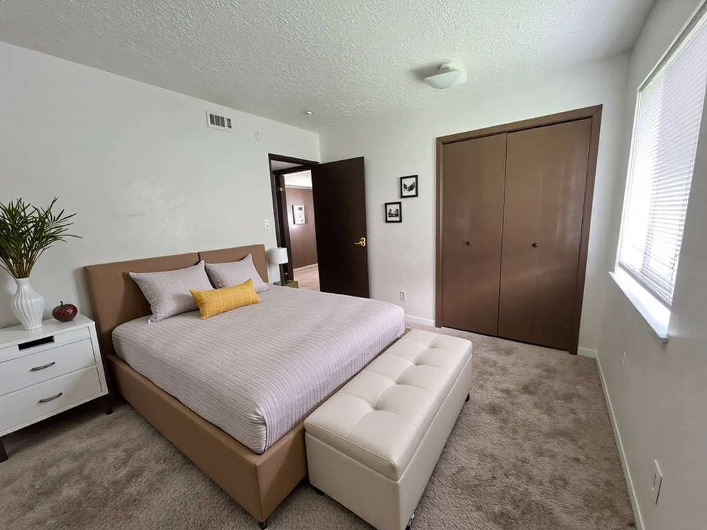 A bedroom with a large bed and a white dresser.